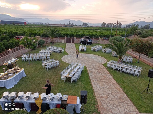 An outdoor event with tables set up for dining, a stage, and a scenic backdrop of mountains and greenery.