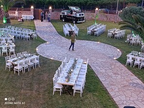 An outdoor event with tables and chairs arranged in a circular pattern on a stone-paved area.
