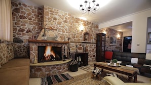 Uma sala de estar acolhedora com lareira de pedra, sofá, mesa de centro e um tapete estampado.