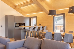 Une cuisine moderne avec des meubles gris et un coin repas avec des chaises grises.