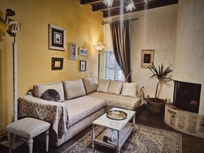 Cozy living area with a comfortable sofa, side table, and fireplace, complemented by framed pictures and a traditional rug.