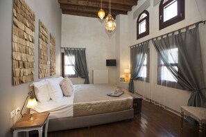 Cozy retreat with a large bed, nightstand, and bench, surrounded by decorative wall art and natural light.