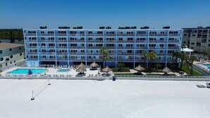 Een hotel met meerdere verdiepingen en een zwembadgedeelte, inclusief een kleiner zwembad en ligbedden.