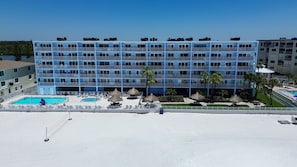 A multi-story hotel with a pool area, including a smaller pool and lounge chairs.
