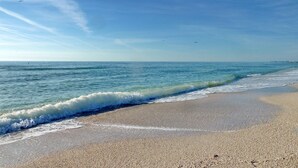 A beach with waves gently lapping at the shore under a clear sky.