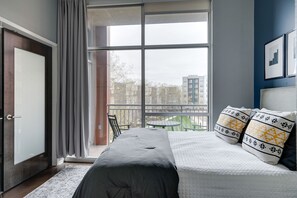 A bedroom with a large window, a bed, a chair, and a view of buildings outside. - Smart, Stylish Music City Condo - Concierge, Restaurants, Gym, Rooftop Patio, Parking (Nashville)