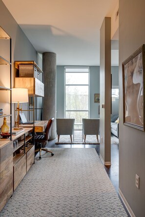 A modern office space with a desk, chairs, and a large window.