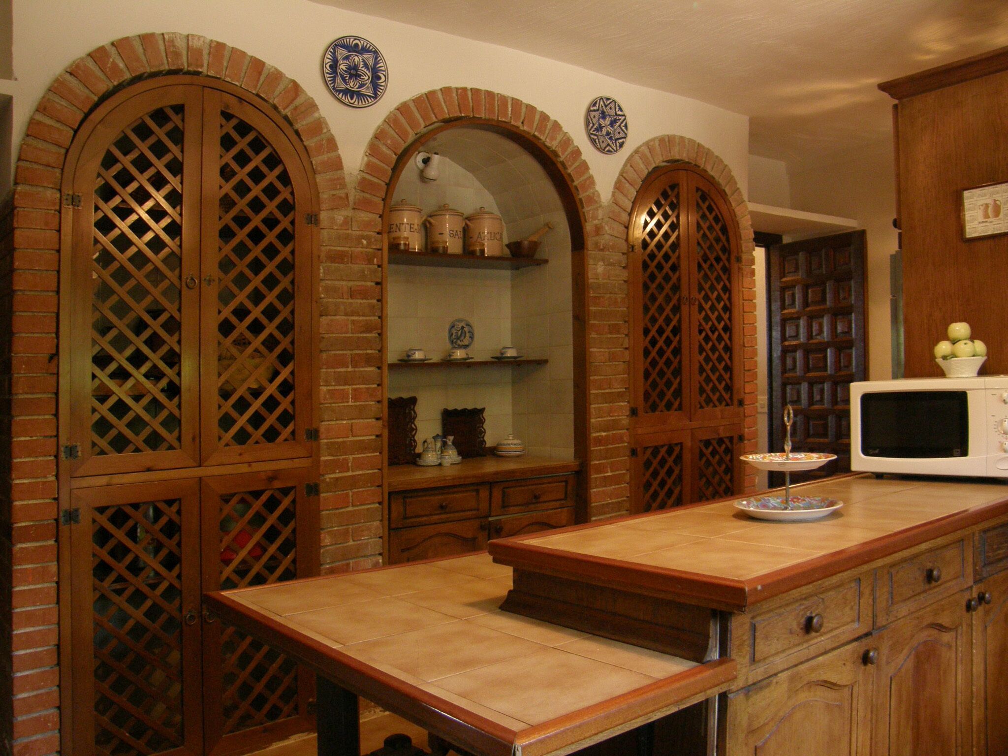 A kitchen with wooden cabinets, a countertop, and a microwave.