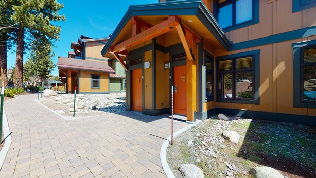 Un hôtel avec un chemin en briques menant à une entrée en bois dotée de portes numérotées.