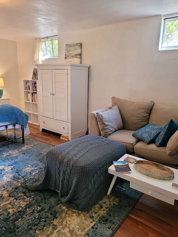 A cozy living room with a beige sofa, a patterned rug, a white cabinet, and a bookshelf.