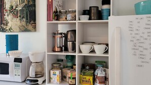 Ett kök med en kaffebryggare, burkar och ett kylskåp.