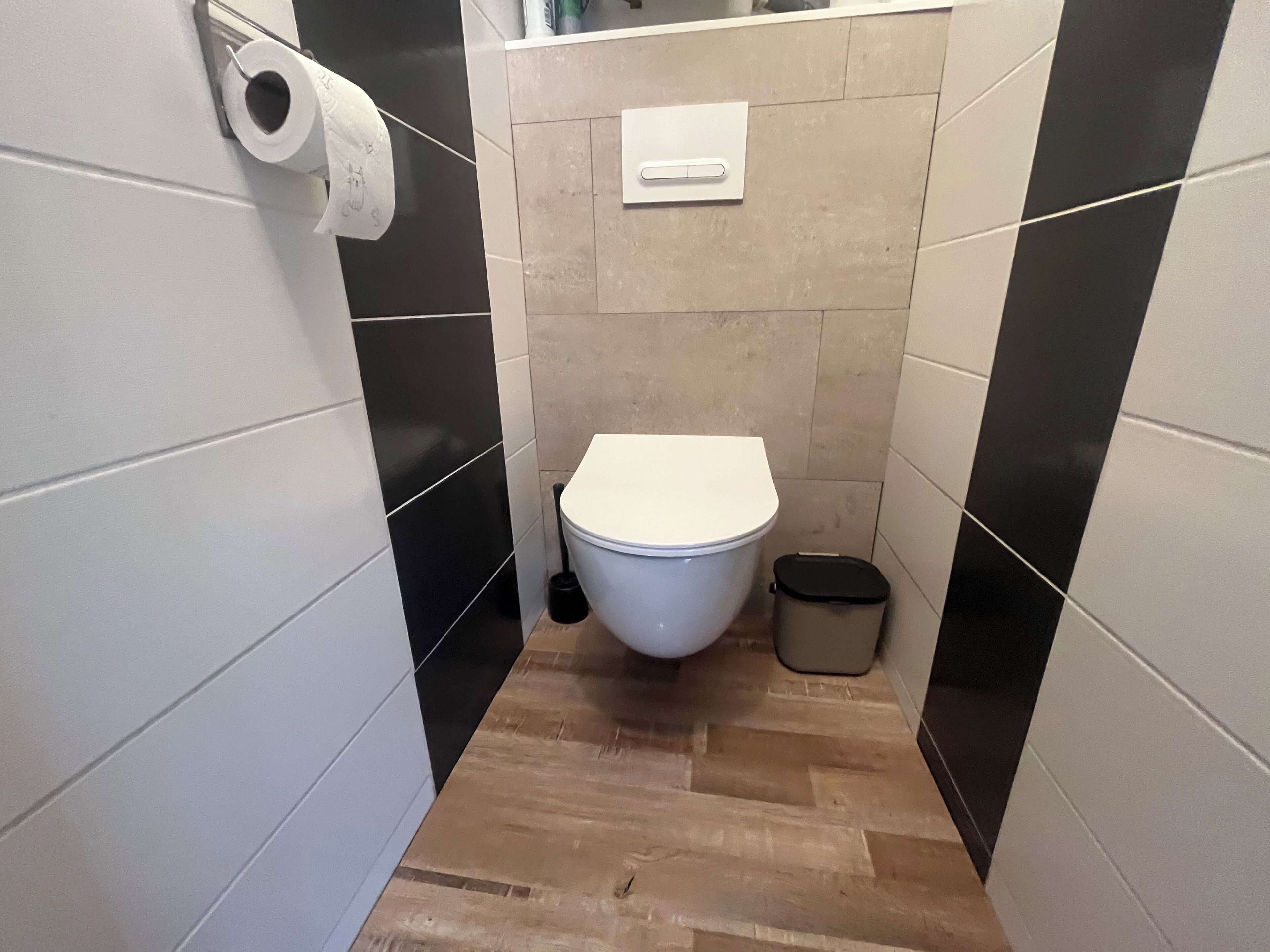 A small, narrow bathroom with a toilet, a bidet, and a trash bin.