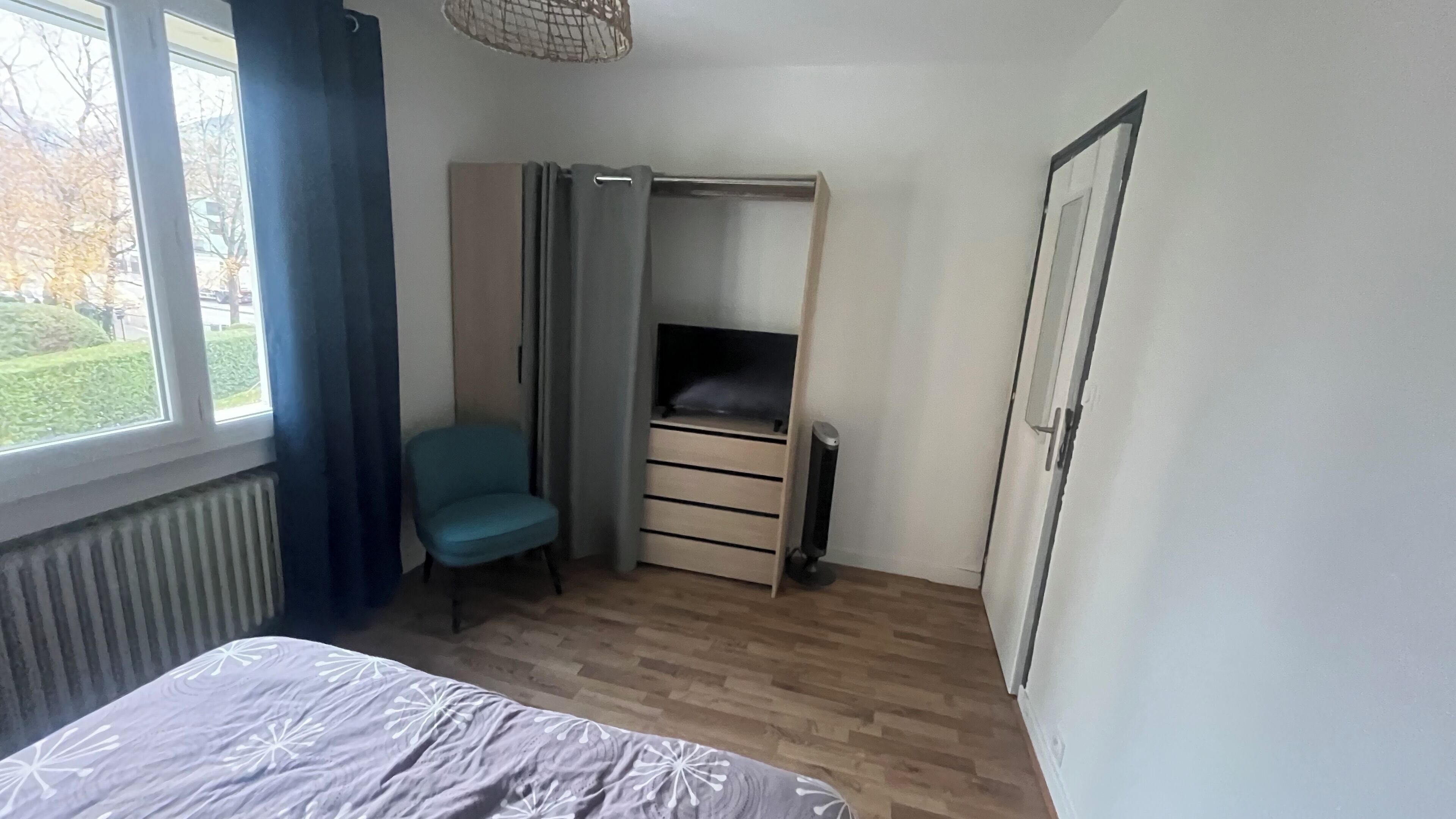 Une chambre à coucher comprenant un lit, une chaise, une armoire et un radiateur.