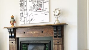A cozy living room with a fireplace, a sofa, and a patterned throw. - Short breaks available!! (St Davids)