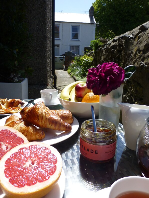 Et morgenbord med croissanter, grapefrugt, en skål med frugt og et syltetøjsglas.