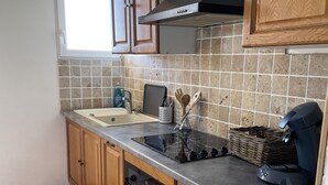 Une cuisine avec des meubles en bois, un four encastré, une cuisinière à gaz et un revêtement mural composé de carreaux carrés.