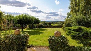 Ein Garten mit einem Kiesweg, der zu einer Aussicht auf die Landschaft führt.