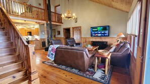A wooden staircase leading to a lofted area with a dining table, chairs, and a television. - El Cabitan: 4BR Scenic Mountain Views, Hot Tub, Game Room & Fire Pit (West Jefferson)