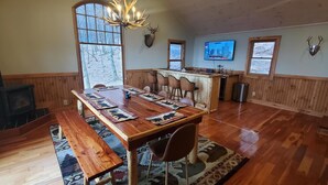A wooden dining area with a large table, benches, and a fireplace. - El Cabitan: 4BR Scenic Mountain Views, Hot Tub, Game Room & Fire Pit (West Jefferson)