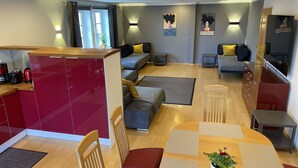 Een moderne woonkamer met een keukenhoek, een eettafel met stoelen en een zithoek.