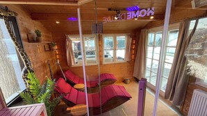 Een gezellige kamer met houten details, een hangstoel en een groot raam met uitzicht op de omgeving.