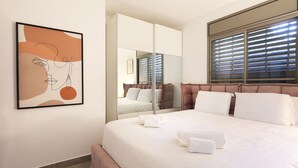 Moderni hotellihuone, jossa on suuri sänky, peili ja seinällä oleva taideteos, joka on kehystetty.