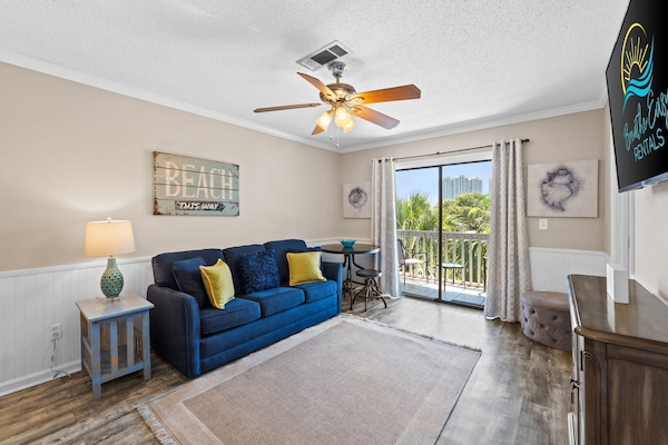 Bright living room with comfy sofa, pops of color, and coastal charm.