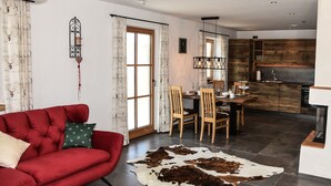 Un salon moderne avec un canapé rouge, une table à manger en bois et une cuisine dotée de meubles de couleur bois foncé.