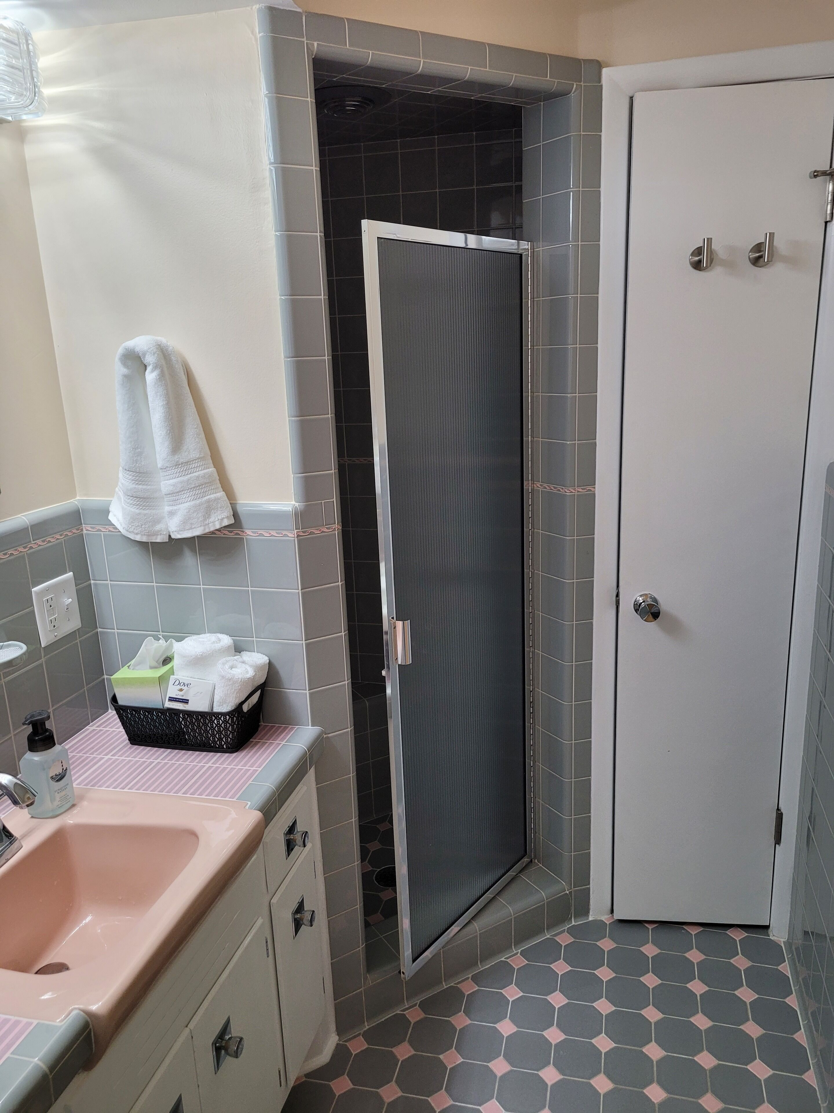 Baño con ducha, lavamanos y toallero.