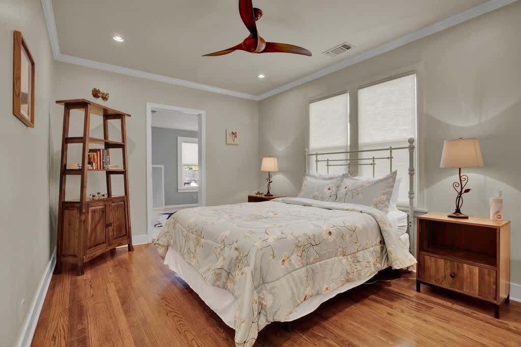 A bedroom with a bed, bedside tables, a wooden cabinet, a ceiling fan, and a window.