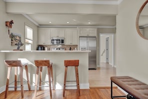 A modern kitchen with white cabinets, stainless steel appliances, and a wooden island with bar stools.