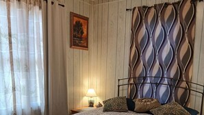 Ein Schlafzimmer mit einem Bett, einem Nachttisch, einer Lampe und einem gemusterten Kopfteil.