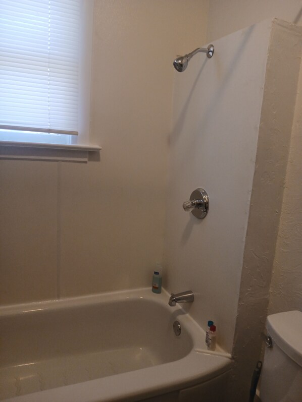 Un baño con bañera, cabezal de ducha e inodoro.