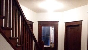 Eine Holztreppe führt zu einer Tür mit einem Fenster.