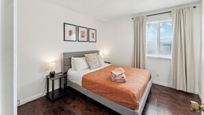 A modern bedroom with a bed, bedside tables, and a window with curtains. - Wonderful 3 bedroom/2 bath, close to everything! (Scottsdale)