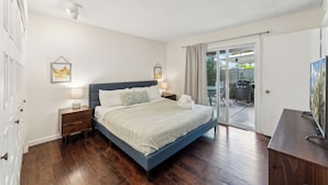 A bedroom with a bed, bedside tables, a TV, and a sliding glass door leading to an outdoor area. - Wonderful 3 bedroom/2 bath, close to everything! (Scottsdale)