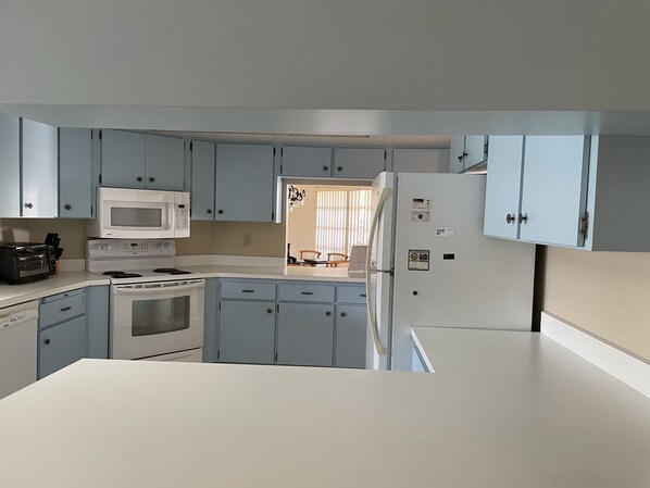 Compact kitchen with microwave, stove, and refrigerator, perfect for small living spaces.