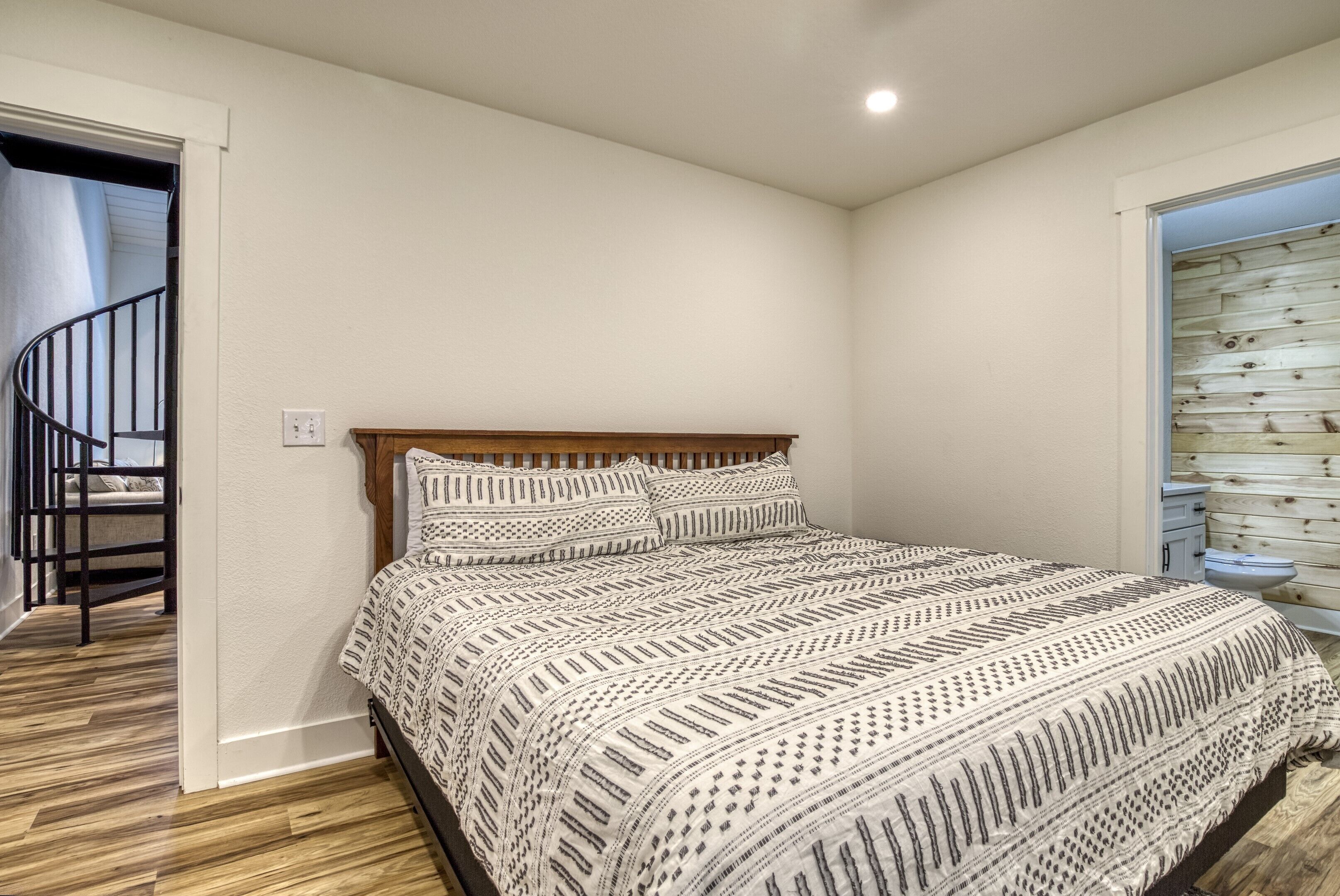 A bedroom with a wooden bed, a white wall, and a wooden floor.