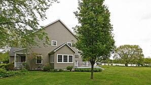A two-story house with a front porch, a small deck, and a lawn. - Tranquil  Beautiful Waterfront  Near Historic St. Michaels & Royal Oak (easton)
