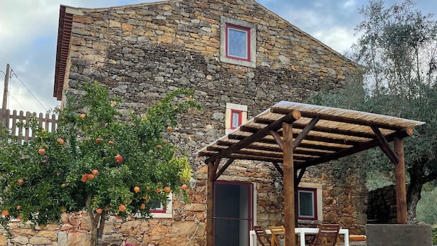 A stone building with a wooden pergola and a potted plant in front. - Unique Experience in the Heart of Nature (Chãos)