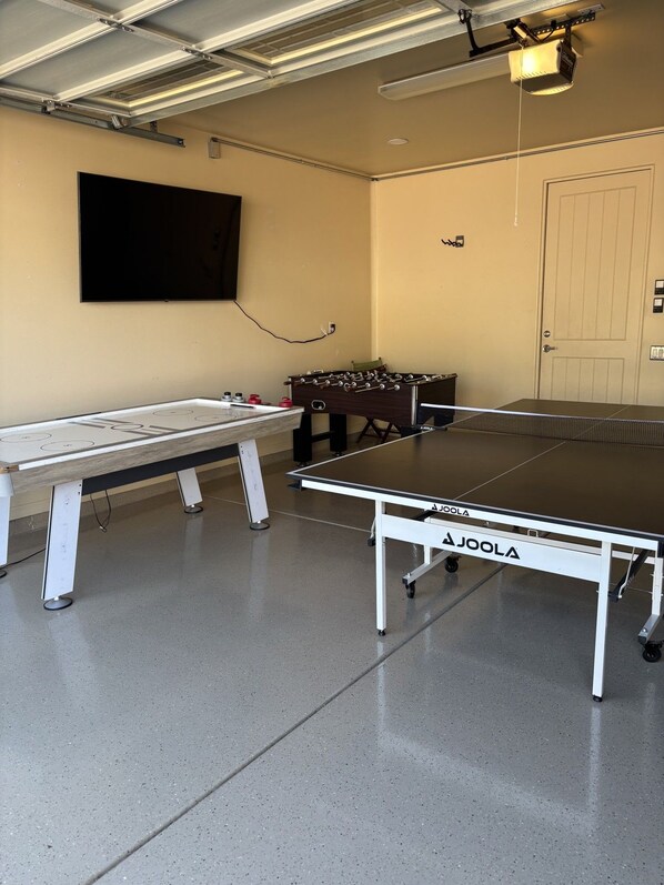 A ping pong table with a net, a foosball table, and a television mounted on the wall. - Desert Tranquility 4 Bedroom with Heated Pool (Scottsdale)
