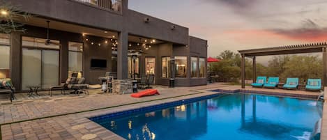 A modern outdoor pool area with a covered seating area and lounge chairs.