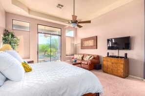 Quarto com cama grande, ventilador de teto, televisão e vista para o exterior.