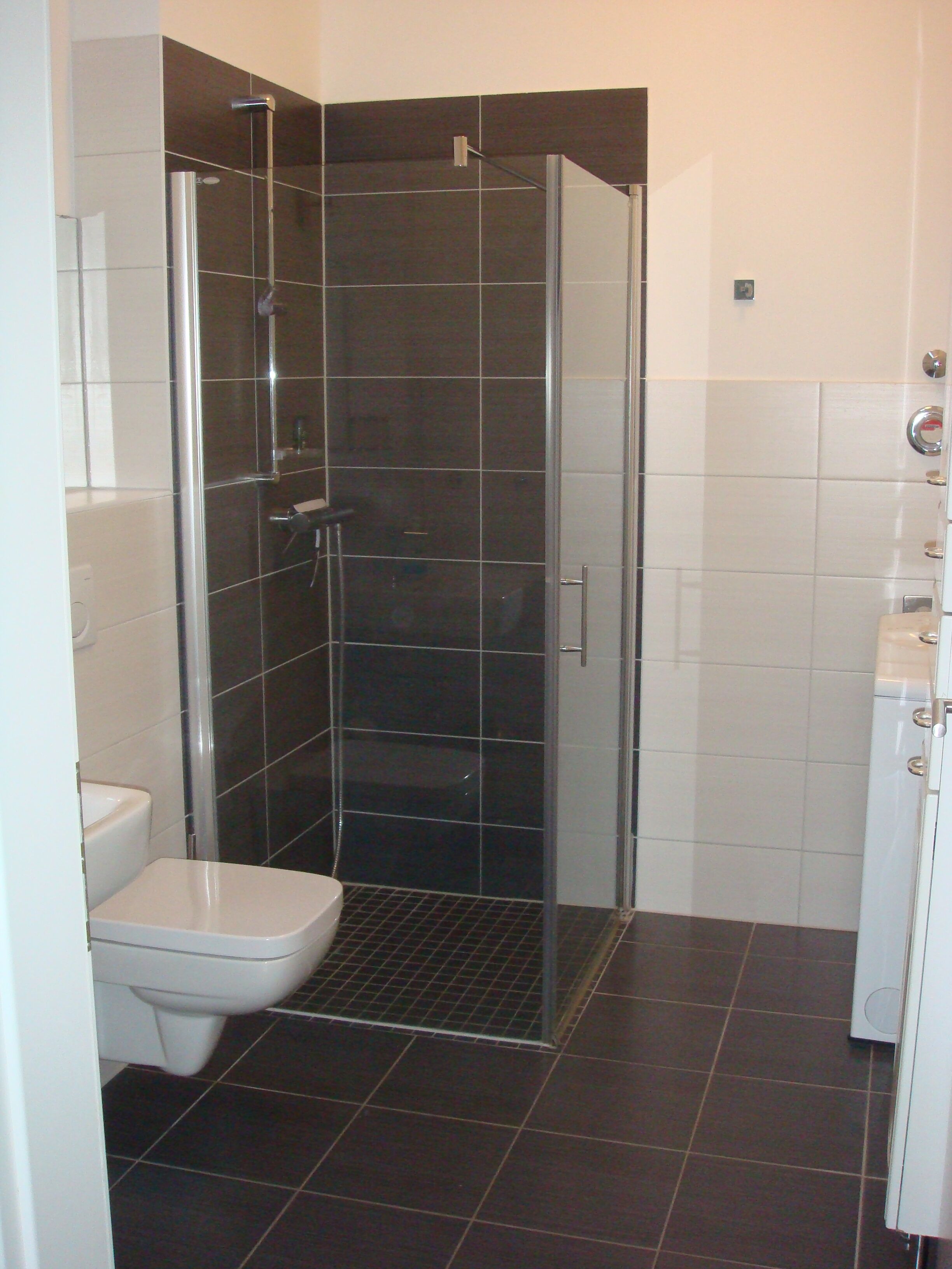 Une salle de bain avec une douche à parois de verre, des toilettes blanches et un lavabo blanc.