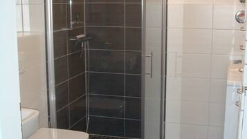 Une salle de bain avec une douche à parois de verre, des toilettes blanches et un lavabo blanc.