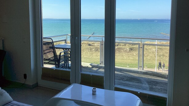 A room with a large sliding glass door leading to a balcony with a view of the ocean. - 2 balconies directly by the sea, living room, fireplace, 1 bedroom, kitchen, modern bathroom with shower/WC, washing machine. (Glowe)