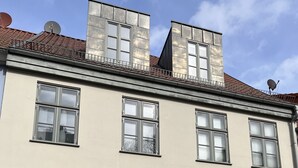 A building with a symmetrical facade, multiple windows, a central green door, and a satellite dish on the roof. - Live in the center, enjoy peace and quiet (Greifswald)