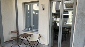 A patio area with a table and chairs, a window, and a sliding glass door leading to an interior space. - Live in the center, enjoy peace and quiet (Greifswald)