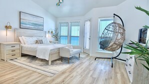A bedroom with a bed, bedside tables, a hanging chair, and a large window.