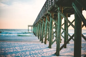 A wooden pier extending into the ocean with a clear sky above.